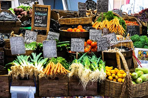 Farmers market display of produce: leeks, carrots, squash and tomatoes